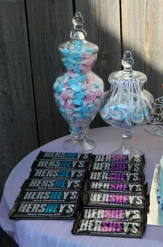 there are candy bars and candies on the table with other sweets in glass vases