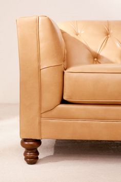 a tan leather chair sitting on top of a white floor