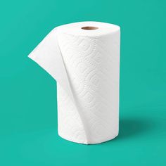 a roll of white toilet paper sitting on top of a green surface with an intricate design