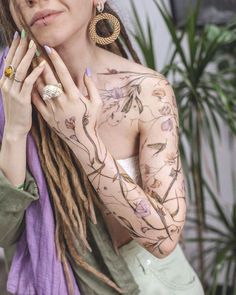 a woman with dreadlocks and tattoos holding her hand up to her face while looking at the camera