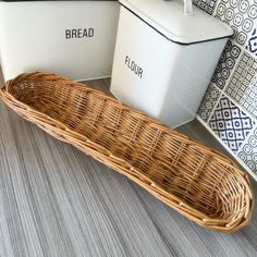 a wicker basket sitting on the floor next to two bread bins