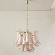 a pink chandelier hanging from a ceiling in a room with white walls and flooring