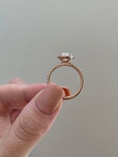 a hand holding a ring with a diamond on it