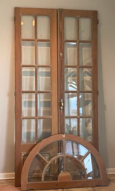 an old wooden grandfather clock sitting in front of two glass doors with wood trimmings