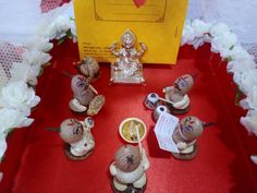 small figurines are sitting on a red tablecloth with white flowers and a yellow box