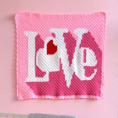 a crocheted love sign hanging on the wall next to a baby crib