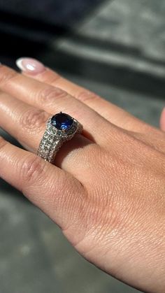 a woman's hand with a ring on it and a blue stone in the middle