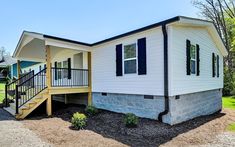 a mobile home with stairs leading up to the front door and second story porch area