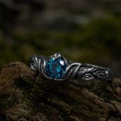 a ring with a blue stone in the center on top of a tree branch trunk