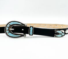 The Xena Belt features black Italian leather adorned with silver oval rivet details and a silver-plated buckle set with a turquoise-colored inlay. This striking belt adds a bold, Southwestern-inspired touch to your look. Details: Material: Black Italian leather Buckle: Western style buckle selt with turquoise inlay Design: Western-inspired Origin: Leather sourced from Italy, made in the USA Western Silver Embroidered Belt, Black Western Belt, Western Silver Belt With Buckle Closure, Western Black Belt Buckles With Silver Detail, Luxury Silver Southwestern Belt Buckles, Inlay Design, Chain Belts, Leather Buckle, Small Handbags