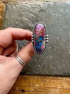 Handmade Spiny Oyster Shell + Purple Mohave Kingman Turquoise and sterling silver statement ring.  -Ring will fit US size 8.5 Vintage American Southwest style design. Striking pink, blue, purple, orange colored stone with copper/gold colored inclusions. Twisty rope trim, Hand polished, rustic looking patina and high polish finish. Hand stamped Indian style Arrow and Rising Sun hallmark on backside. Chunky, triple split style ring shank/band.   Turquoise stone is a composite of different material Collectible Turquoise Cabochon Ring, Multicolor Cabochon Jewelry, Unique Multicolor Turquoise Cabochon Ring, Unique Multicolor Cabochon Turquoise Ring, One-of-a-kind Artsy Sterling Silver Jewelry, Artsy One-of-a-kind Sterling Silver Jewelry, One-of-a-kind Silver Turquoise Ring Gift, Unique Multicolor Sterling Silver Turquoise Ring, Multicolor Turquoise Ring In Sterling Silver