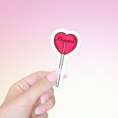 a hand holding a sticker with the word physland on it and a heart shaped lollipop