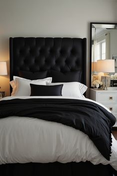 a bed with black and white sheets in a bedroom next to two lamps on either side of the bed