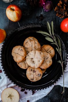 some cookies are on a black plate next to apples