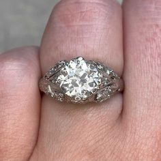 a woman's hand holding an old - fashioned diamond engagement ring with filigrees