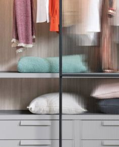 an open closet with clothes hanging on the shelves and folded towels in front of it