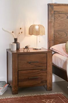 a bedroom with a bed, night stand and lamp on the nightstand next to it