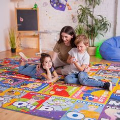 a woman and two children laying on a colorful rug in the middle of a room