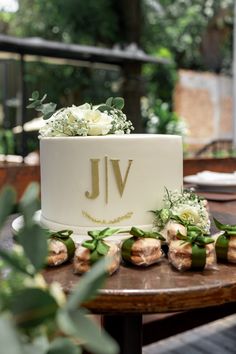 a white wedding cake sitting on top of a wooden table next to flowers and greenery