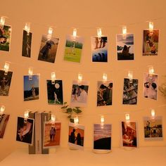 several pictures are hung on a string with candles and lights strung from the strings above them