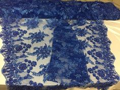 a blue and white lace with flowers on the edge is laying on a tablecloth