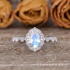 an engagement ring with a white topaz surrounded by diamonds and roses in the background