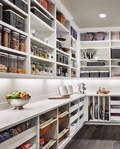 a kitchen with white cabinets and shelves filled with food