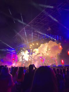 a large group of people standing on top of a stage with fireworks in the air