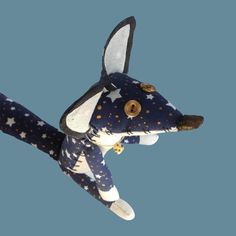 a stuffed animal with stars on it's head is flying through the air in front of a blue sky