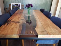 a wooden table with blue chairs around it and a vase filled with flowers on top