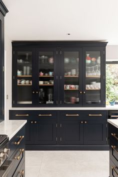 a large kitchen with black cabinets and marble counter tops, gold trimmings on the doors