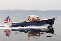 a small blue boat with an american flag on the front is traveling in calm water