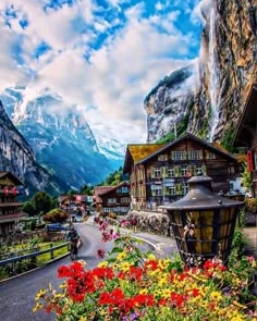 an image of a village with flowers in the foreground and mountains in the background