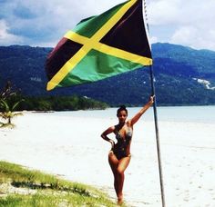 a woman in a bathing suit holding a flag on the beach