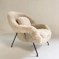 a chair made out of sheep's wool with black legs and an iron base