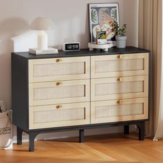 a black and white dresser sitting in a living room next to a painting on the wall