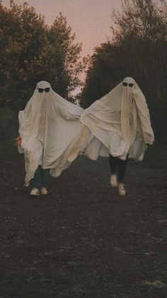 two people in white cloths are walking through the woods