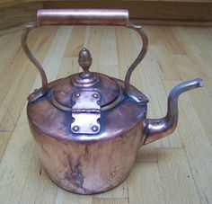 an old tea kettle sitting on top of a wooden floor