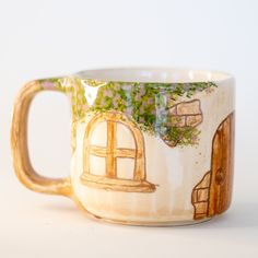 a ceramic coffee cup with an image of a house on it's front and side