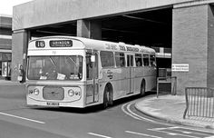 a black and white photo of a bus in front of a building