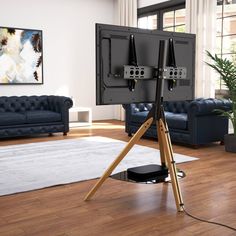 a living room with two televisions on top of a tripod in front of a couch