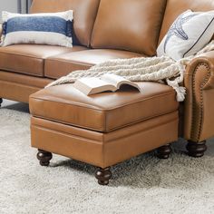 a brown leather couch sitting on top of a white rug next to a wooden chair