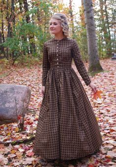 This attractive dress has a jewel neckline, front button closure and long sleeves. This dress also features our three-paneled full skirt with pockets. Hand wash or machine wash and dry gently. 100% sturdy cotton. The model is wearing boots, and a crinoline, which are priced separately. Designed and made proudly by Recollections in America! The following are approximate finished measurements and include room for ease of movement.  BustWaist (in inches) XS36.528 S39        29.5 M41        31.5 L45 Pioneer Work Dress, Fall Long Sleeve Dress With Button Cuffs, Classic Fall Dresses With Covered Buttons, Fitted Long Sleeve Cotton Prairie Dress, Modest Buttoned Fall Dresses, Classic Long Sleeve Brown Dress, Classic Dresses With Covered Buttons For Fall, Modest Fall Dresses With Buttons, Modest Buttoned Dresses For Fall