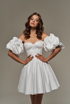 a woman in a white dress posing for the camera with her hands on her hips