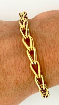 This exquisite bracelet is a true designer piece from Italian luxury brand UNOAERRE. Crafted from high-quality 14k yellow gold, this intertwined etched bracelet is both stylish and durable. The wrap and chain style adds a touch of elegance to any outfit, while the 7.5 inch length ensures a comfortable fit. With no stone and featuring a unique design, this bracelet is perfect for those who want to stand out from the crowd. The piece weighs 5.8g and is stamped with the brand's signature mark. Add Luxury Rectangular Yellow Gold Bracelet, Luxury Yellow Gold Jewelry With Rectangular Links, Luxury Etched Gold Bracelet, Luxury Gold Etched Bracelet, Luxury Rectangular Gold-tone Jewelry, Luxury Gold-tone Rectangular Jewelry, Luxury Oval Link Hallmarked Chain Bracelet, Luxury Oval Link Chain Bracelet For Anniversary, Elegant 14k Gold Bracelet With Lobster Clasp