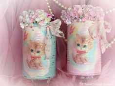 two little bottles with kittens on them are decorated with flowers and pearls, sitting next to each other