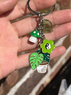 a person is holding a keychain with a plant and mushroom on it