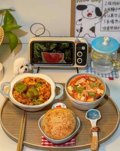 three bowls of food are on a tray with a toaster oven and spoons