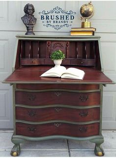 an old desk has a book on it and a vase with a plant in it