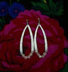 pair of white hoop earrings sitting on top of a pink flower